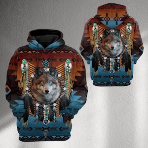Op de afbeelding: Een hoodie met een gedetailleerd wolvenportret met turquoise en veermotieven. Het ontwerp bevat patronen geïnspireerd op de inheemse bevolking van Amerika in tinten bruin, blauw en oranje. De achterkant van de hoodie weerspiegelt het ontwerp aan de voorkant.