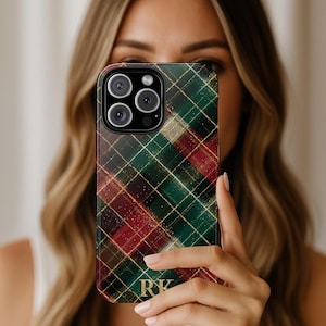May include: A smartphone case with a plaid pattern in shades of green, red, and gold. The case has a glossy finish and features a monogram with the letters "RK". The phone case is designed to protect the phone.