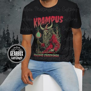 May include: Black t-shirt featuring a Krampus graphic in red, green, and gold. The design includes the text "KRAMPUS" and "SEASONS CREEPINGS". A Gearbox Customs logo is visible on the left side of the shirt.