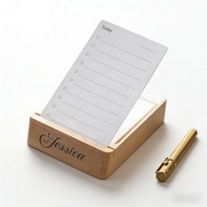 Puede incluir: Un organizador de escritorio de madera con un bloc de notas que dice "Today" y un bolígrafo dorado. El organizador tiene el nombre "Jessica" grabado en la parte delantera. El bloc de notas tiene líneas y círculos para una lista de tareas.