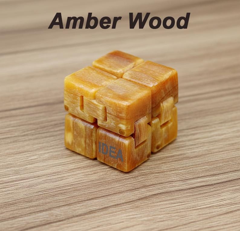 Puede incluir: Un cubo de madera de color &aacute;mbar con la palabra "IDEA" impresa en un lado. La parte superior del cubo tiene las palabras "Amber Wood" impresas en negro. El cubo est&aacute; hecho de varios bloques conectados.