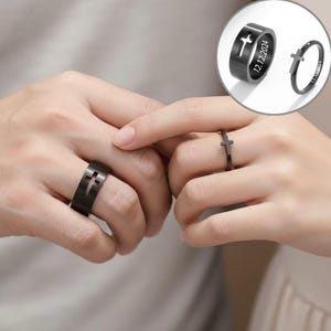 Op de afbeelding: Zwarte ringen met kruisontwerpen. Eén ring heeft een uitgesneden kruis, de andere een klein kruisje erbovenop. De ringen worden op vingers getoond, met een close-up van de ringdetails. Een derde afbeelding toont de ring met de datum 12.12.2024.