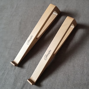 May include: Two light-colored wooden laptop stands with a minimalist design. Each stand has a sloped surface and a cutout for ventilation. The name "Jennifer" is elegantly inscribed on each stand.