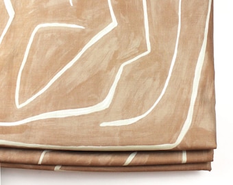 May include: A brown roman shade with a white abstract pattern. The shade is folded and the fabric is textured.