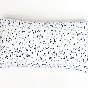 May include: A white cushion with a blue and light blue polka dot pattern.