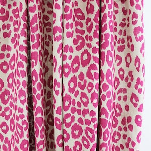 May include: Pink and beige leopard print curtains with a black curtain rod and gold hooks.