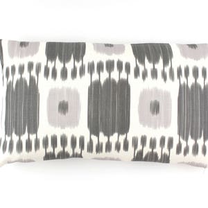 May include: A white lumbar pillow with a gray and light purple ikat pattern.