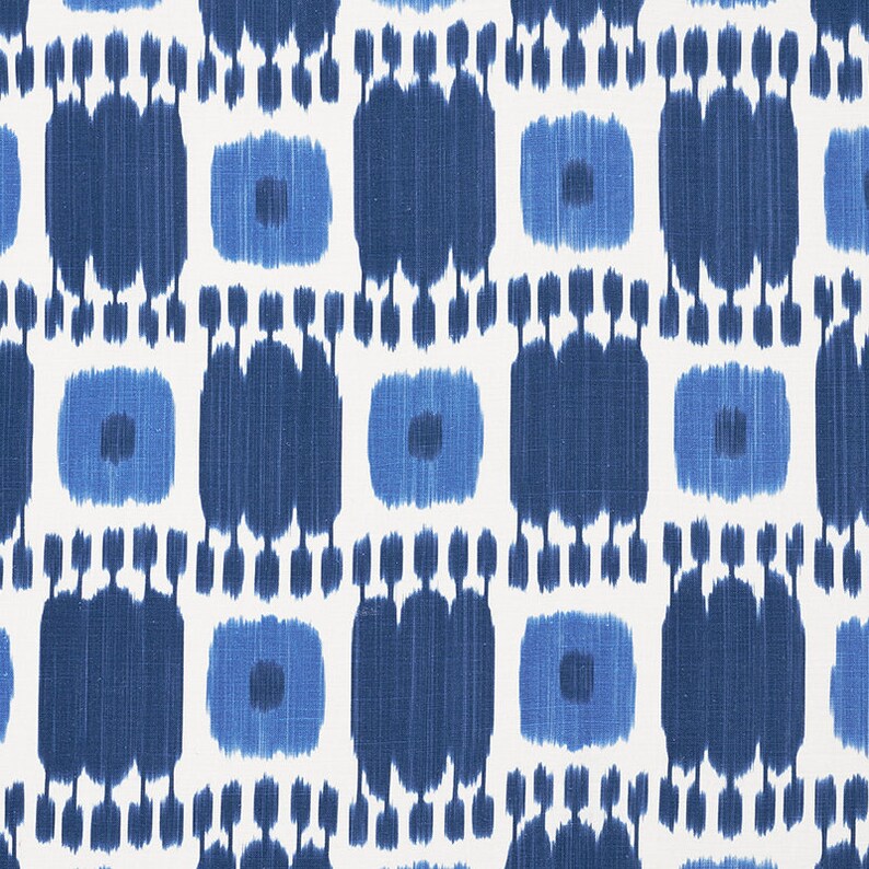 May include: A white fabric with a blue and white ikat pattern. The pattern is made up of repeating squares with a small circle in the center.
