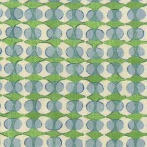 May include: A repeating pattern of green, blue, and off-white shapes. The design features overlapping blue circles and green diamond shapes on an off-white background. The fabric has a textured appearance, suggesting a woven material. The overall aesthetic is retro and geometric.