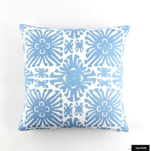 Puede incluir: Coj&iacute;n cuadrado con un patr&oacute;n floral azul repetido sobre fondo blanco. El coj&iacute;n es cuadrado y est&aacute; hecho de tela suave. El dise&ntilde;o presenta una disposici&oacute;n sim&eacute;trica de flores estilizadas.