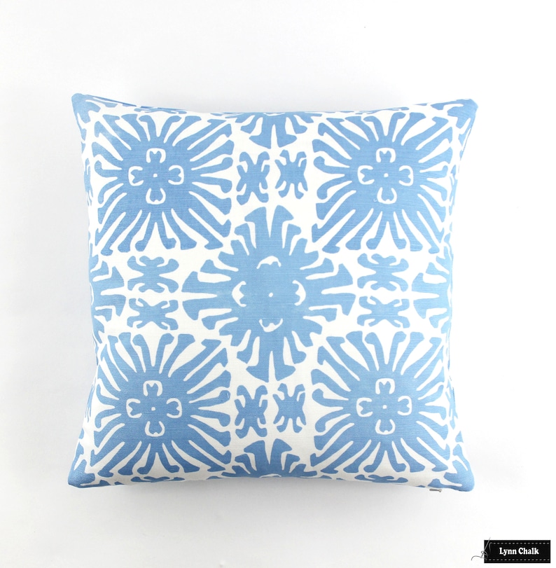 Puede incluir: Coj&iacute;n cuadrado con un patr&oacute;n floral azul repetido sobre fondo blanco. El coj&iacute;n es cuadrado y est&aacute; hecho de tela suave. El dise&ntilde;o presenta una disposici&oacute;n sim&eacute;trica de flores estilizadas.