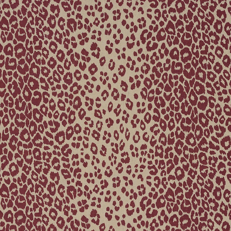 May include: A beige fabric with a repeating pattern of maroon leopard spots.