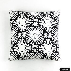 May include: Black and white throw pillow with a geometric pattern of stylized flowers. The pillow is made of a soft, durable fabric and is perfect for adding a touch of modern style to any room.