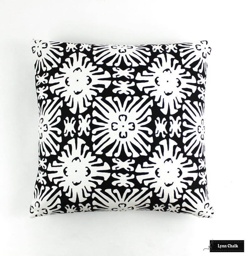 May include: Black and white throw pillow with a geometric pattern of stylized flowers. The pillow is made of a soft, durable fabric and is perfect for adding a touch of modern style to any room.