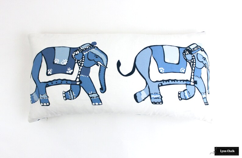 Puede incluir: Una almohada rectangular blanca con dos elefantes estilizados azules impresos en ella. Los elefantes est&aacute;n mirando en direcciones opuestas y tienen mantas de silla con patrones azules y blancos.