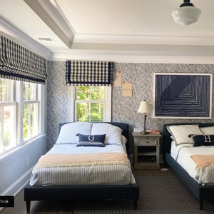 May include: Two twin beds with navy blue and white checkered bedding and matching window treatments. The room has a blue and white patterned wallpaper and a framed abstract art print above a nightstand.