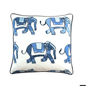 Puede incluir: Una almohada blanca con un borde negro presenta un patr&oacute;n repetido de elefantes azules. Los elefantes est&aacute;n estilizados y tienen un dise&ntilde;o indio tradicional.