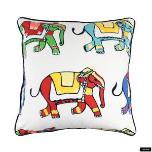 Puede incluir: Almohada blanca con borde negro que presenta un patr&oacute;n repetitivo de elefantes coloridos. Los elefanten est&aacute;n dibujados en un estilo simple con acentos rojos, amarillos, azules y verdes.