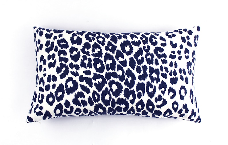 May include: A white rectangular pillow with a navy blue leopard print pattern.