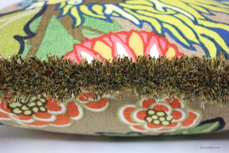 May include: A brown throw pillow with a colorful floral pattern and a brown fringe trim.