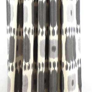 May include: Gray and white patterned curtains with a geometric design. The curtains are hung on a black curtain rod.