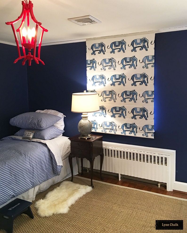 Puede incluir: Una cortina de ventana con estampado azul y blanco con un dise&ntilde;o de elefantes. La cortina est&aacute; colgada en una habitaci&oacute;n con una pared azul, una cama con un edred&oacute;n a rayas azul y blanco, una alfombra blanca y una mesita de noche de madera con una l&aacute;mpara.