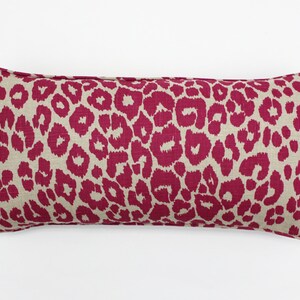May include: A long, rectangular pillow with a pink and beige leopard print pattern.