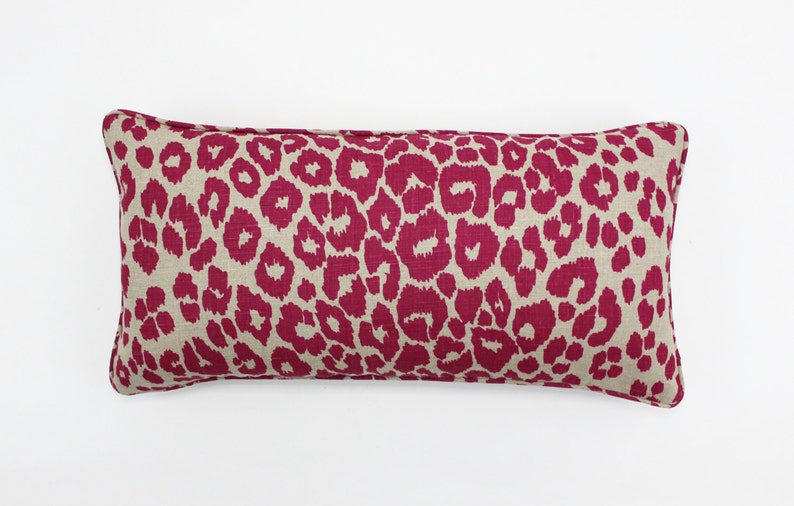 May include: A long, rectangular pillow with a pink and beige leopard print pattern.
