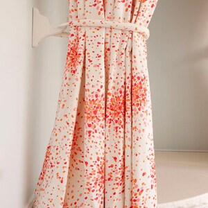 May include: White curtains with a red and orange confetti pattern. The curtains are tied back with a white rope and are hanging from a white hook.