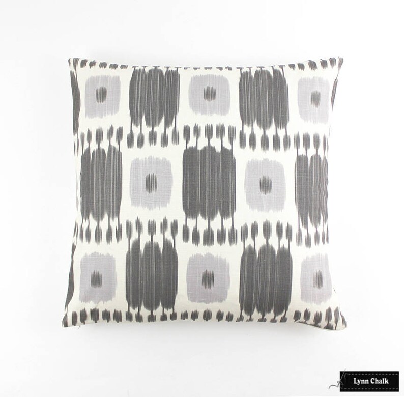 May include: A rectangular throw pillow with a white background and a geometric pattern in shades of gray and light purple.