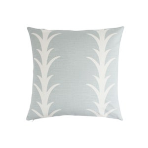 May include: Square decorative pillow with a light blue background and a white, stylized leaf pattern. The pillow has a zipper closure and is designed for home decor.