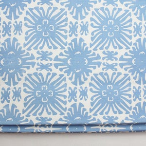 Puede incluir: Tela doblada con un patr&oacute;n repetitivo de dise&ntilde;os florales azul claro sobre un fondo blanco. El patr&oacute;n floral es un dise&ntilde;o estilizado y sim&eacute;trico. La tela parece ser un textil decorativo, posiblemente para la decoraci&oacute;n del hogar.