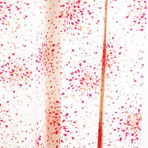 May include: White fabric with a red, pink and orange confetti pattern. The fabric is folded in half and the bottom edge is visible. The text "Lynn Chalk" is visible at the bottom of the image.