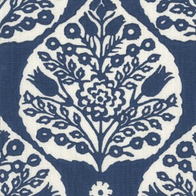 Op de afbeelding: Een witte stof met een blauw bloemenpatroon. Het patroon bevat gestileerde bloemen, bladeren en knoppen. De stof heeft een textuur die lijkt op linnen.