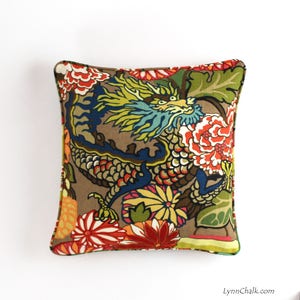 May include: A decorative pillow with a brown background featuring a colorful dragon design with floral accents. The dragon is blue, green, and yellow, and the flowers are red, orange, yellow, and green.