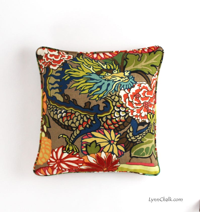 May include: A decorative pillow with a brown background featuring a colorful dragon design with floral accents. The dragon is blue, green, and yellow, and the flowers are red, orange, yellow, and green.