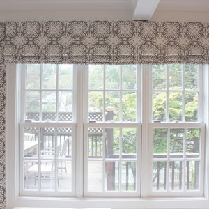 Puede incluir: Una ventana con marco blanco y una cenefa estampada. La cenefa tiene un dise&ntilde;o floral repetido en tonos grises y blancos. La ventana da a una terraza y &aacute;rboles.