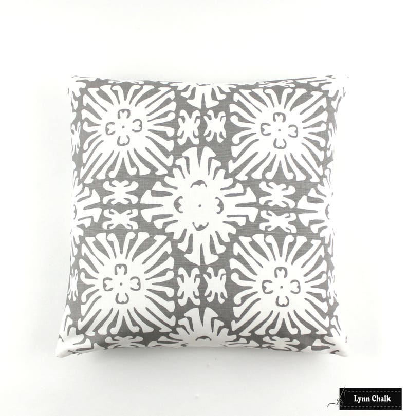 Puede incluir: Coj&iacute;n decorativo cuadrado con un patr&oacute;n geom&eacute;trico gris y blanco. El coj&iacute;n presenta un dise&ntilde;o floral repetido en blanco sobre un fondo gris. El coj&iacute;n es cuadrado y parece estar hecho de tela.