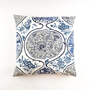 May include: A white throw pillow with a blue and white floral pattern. The pattern features intricate designs of flowers and leaves.