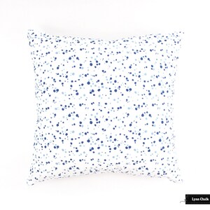 May include: A white square cushion with a blue and light blue confetti pattern.