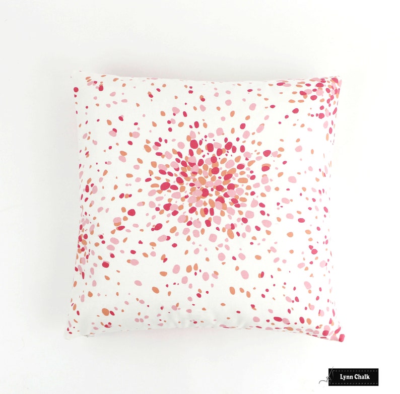 May include: White pillow with a pink and orange confetti pattern. The pattern is concentrated in the centre of the pillow, creating a burst effect.