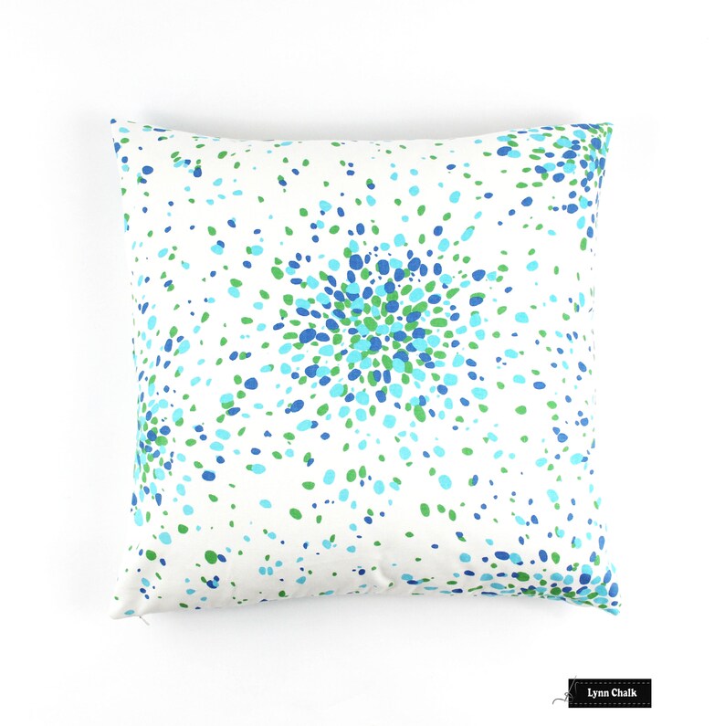 May include: White cushion with a blue and green confetti pattern. The pattern is concentrated in the centre of the cushion and spreads out towards the edges.