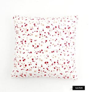 May include: White cushion with a red and pink polka dot pattern. The cushion is made of a soft, comfortable fabric and has a zip closure.