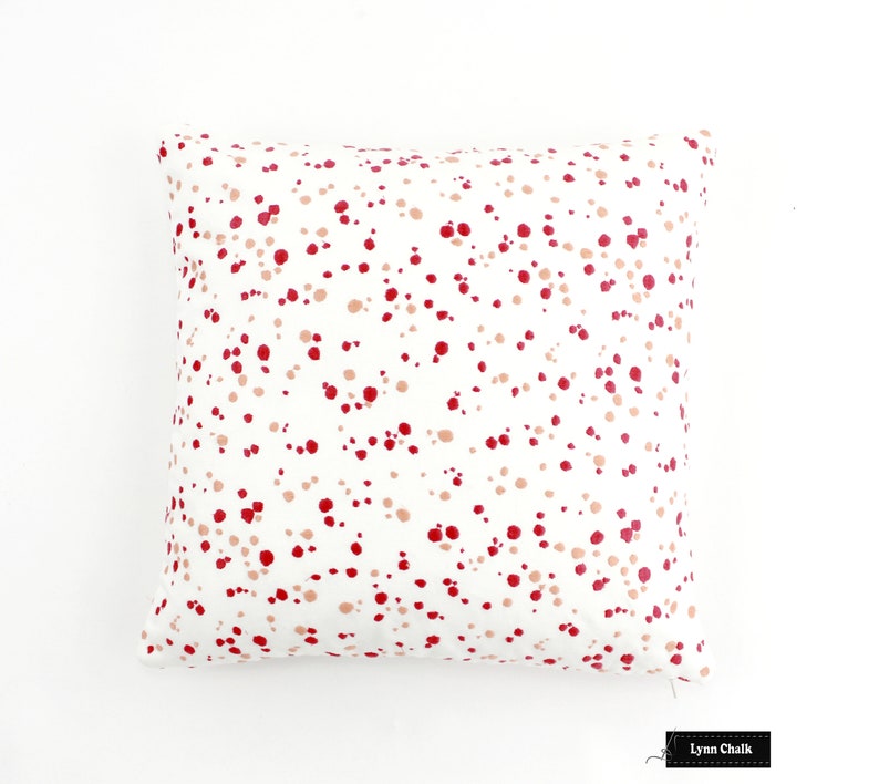 May include: White cushion with a red and pink polka dot pattern. The cushion is made of a soft, comfortable fabric and has a zip closure.