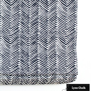 Puede incluir: Una cortina romana blanca y azul marino con un patr&oacute;n de chevron. La cortina est&aacute; hecha de tela y tiene un dise&ntilde;o simple y moderno.
