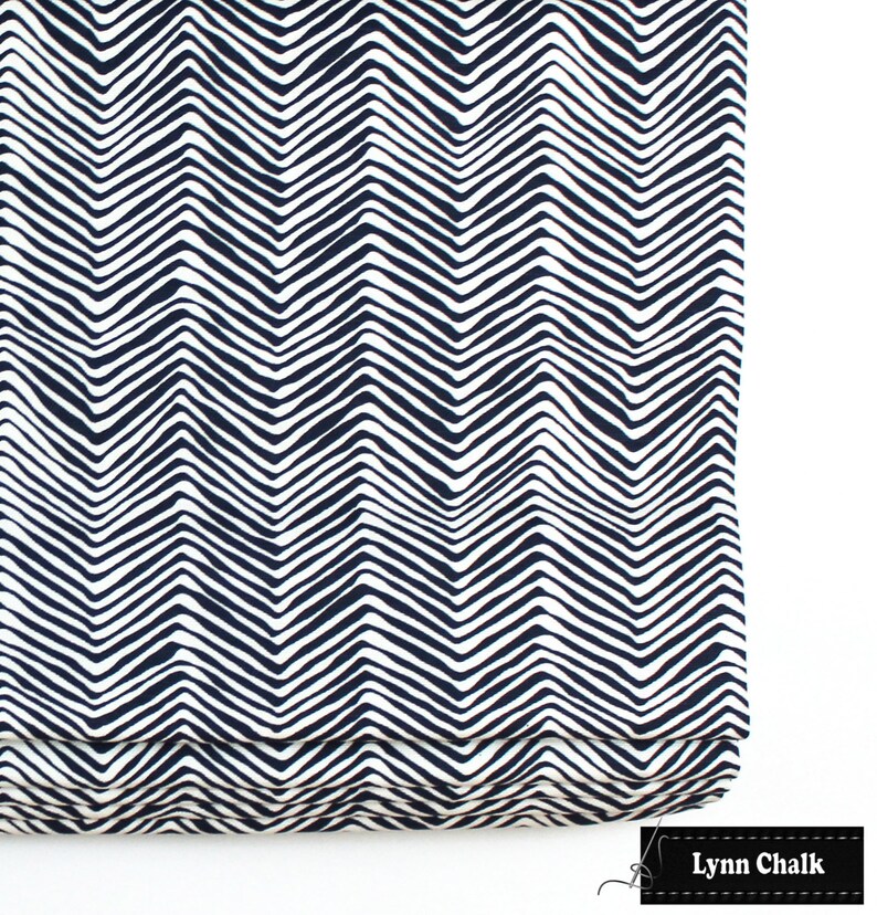 Puede incluir: Una cortina romana blanca y azul marino con un patr&oacute;n de chevron. La cortina est&aacute; hecha de tela y tiene un dise&ntilde;o simple y moderno.