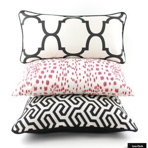 May include: Three decorative throw pillows with black and white geometric patterns. The top pillow has a white background with black geometric shapes. The middle pillow has a white background with pink geometric shapes. The bottom pillow has a black background with white geometric shapes.