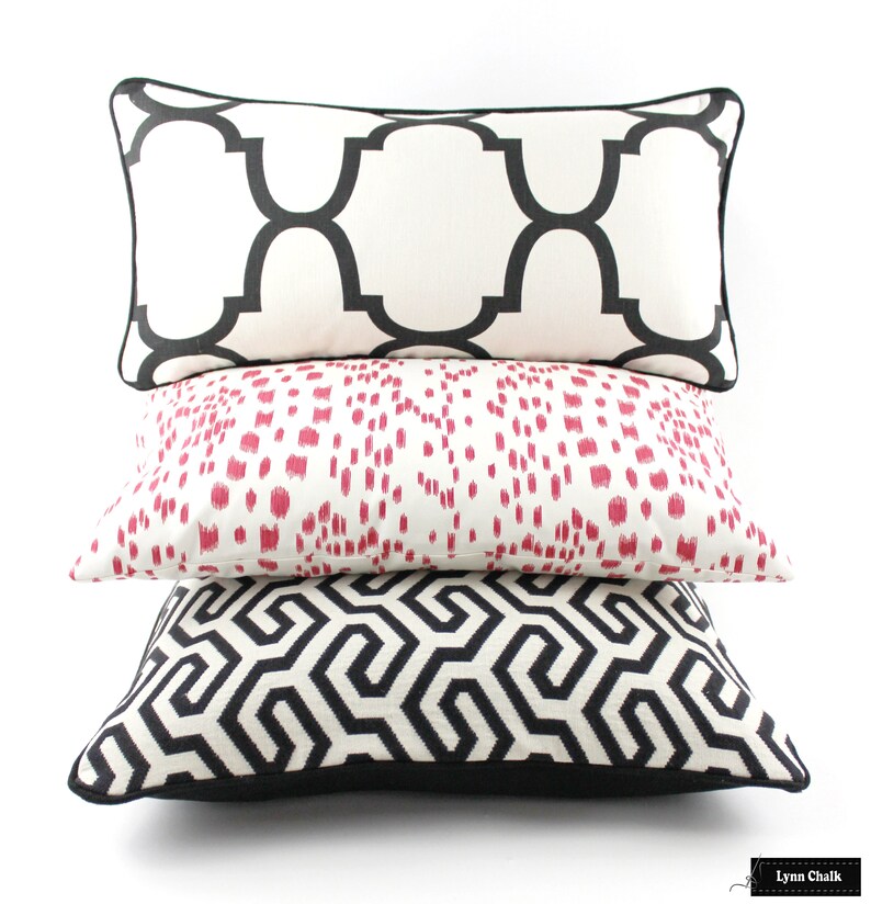 May include: Three decorative throw pillows with black and white geometric patterns. The top pillow has a white background with black geometric shapes. The middle pillow has a white background with pink geometric shapes. The bottom pillow has a black background with white geometric shapes.