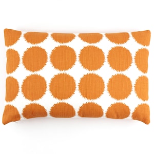 May include: A white pillow with a pattern of orange circles. The circles have a fuzzy texture.