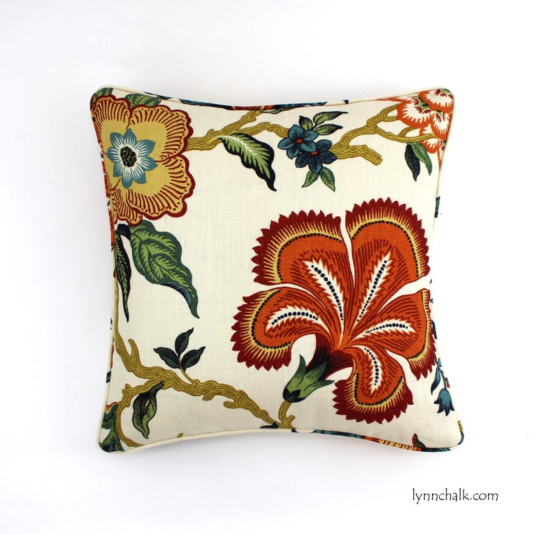 May include: A cream-colored pillow with a floral pattern. The flowers are in shades of orange, red, yellow, and green. The pillow has a white border.